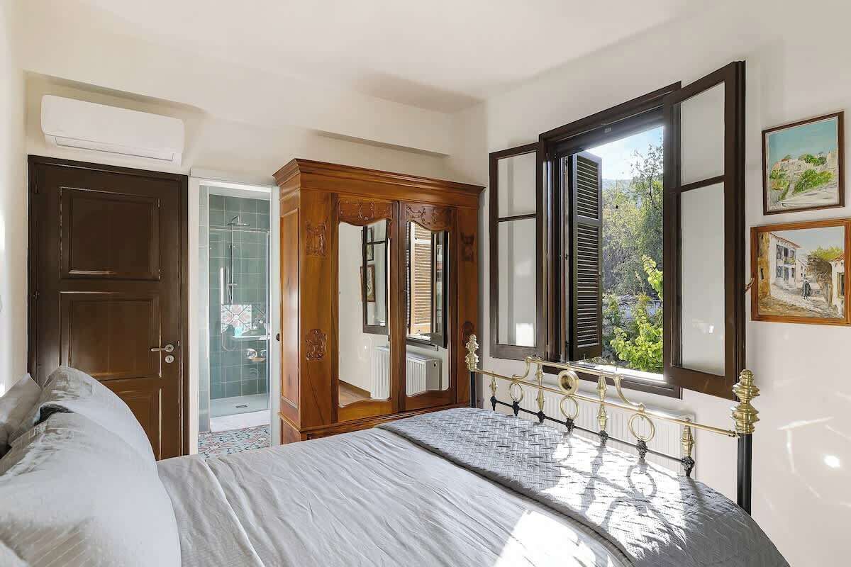 Ein Schlafzimmer mit Bett, Kleiderschrank, Tür und Fenster mit Blick.