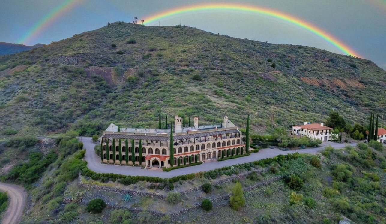 Un edifici històric amb un pati central, envoltat de vegetació i turons.