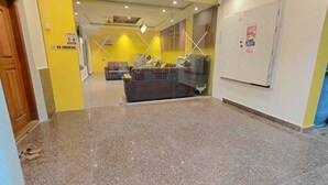 A lobby with a reception desk, a 'No Smoking' sign, and a glass partition. - SM Stay Inn (Bengaluru)