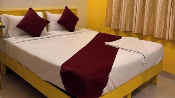 A bed with white linens, two pillows, and a red throw blanket. - SM Stay Inn (Bengaluru)
