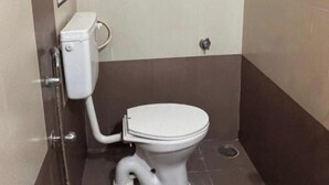 A bathroom with a toilet, a shower, and a hand dryer. - SM Stay Inn (Bengaluru)
