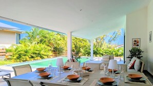 A dining area with a pool view, outdoor seating, and a modern design. - Villa Néréa - 4 Bedrooms and Pool - Near the Lagoon (Saint-Paul)