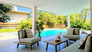 A modern outdoor seating area with two sofas and a coffee table, overlooking a swimming pool and lush greenery. - Villa Néréa - 4 Bedrooms and Pool - Near the Lagoon (Saint-Paul)