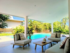 A modern outdoor seating area with two sofas and a coffee table, overlooking a swimming pool and lush greenery. - Villa Néréa - 4 Bedrooms and Pool - Near the Lagoon (Saint-Paul)