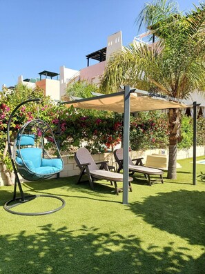 A patio area with a hanging chair, lounge chairs, and a pergola. - Cozy Villa in Vera, Just Steps From the Beach (Vera)