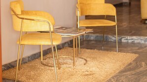 A modern lobby with abstract wall art, a reception desk, and two yellow chairs. - Lacasa Hotel Epe (Epe)