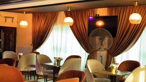A dining area with tables and chairs, a fan, and curtains. - Lacasa Hotel Epe (Epe)
