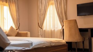 A hotel room with a bed, a chair, a TV, and curtains. - Lacasa Hotel Epe (Epe)