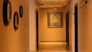A hallway with a polished floor, framed artwork on the wall, and doors on both sides. - Lacasa Hotel Epe (Epe)