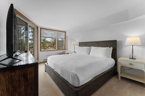 Ein Schlafzimmer mit einem Bett, Nachttischen, einem Fernseher und einem Fenster mit Jalousien.