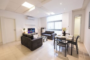 Ein modernes Wohnzimmer mit einer Couch, einem Couchtisch und einem Essbereich mit Stühlen und einem Tisch.