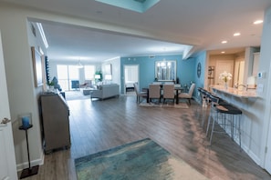 A spacious living area with a dining table, bar stools, and a kitchen area. - 705 Margate, Oceanfront Escape with Resort Amenities (Myrtle Beach)
