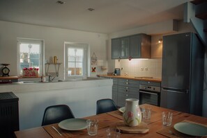A kitchen with a dining table, chairs, a refrigerator, and cabinets.
