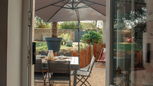 An outdoor patio with a table, chairs, and a large umbrella. - House 5 minutes from Amboise (Chargé)