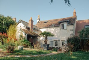 A traditional house with a garden, a potted palm tree, and a small patio area.