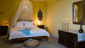 Un dormitorio con cama a dosel, lámparas de noche, un espejo y un aparador con velas.