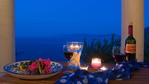 Una mesa con una botella de vino, una copa de vino tinto, una vela y un cuenco de flores.