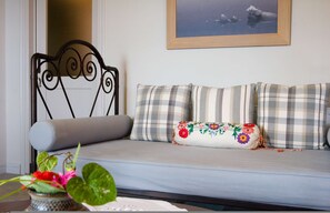 A sofa with plaid cushions, a metal headboard, and a floral pillow. - Stolios Skopelos - Erato Deluxe Panoramic View (Skopelos)