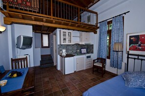 Ein gemütliches Zimmer mit Küchenzeile, Essbereich, einem Bett und einer Treppe, die in ein Obergeschoss führt.