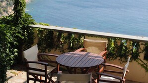 A patio with a table and chairs overlooking a coastal view. - Stolios Skopelos - Terpsichore Split Level Nest (Skopelos)