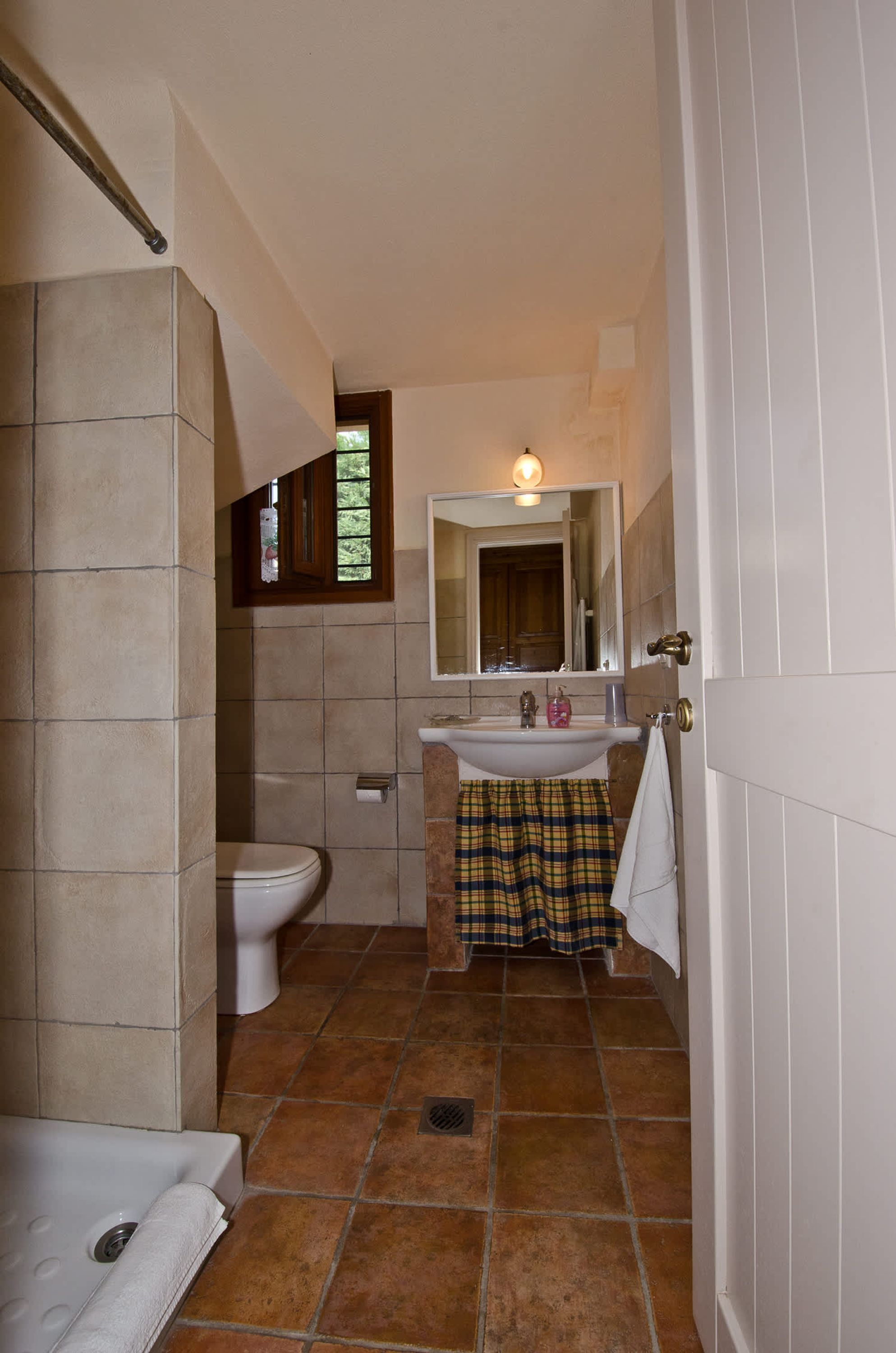 A bathroom with a toilet, sink, and shower area.