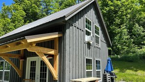 A rustic wooden building with a covered patio, outdoor seating, and a grill area.