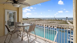 A balcony with a pool, chairs, and a table. - The Big Surf II - Gulf View - Beach Pool and Fun (Gulf Shores)