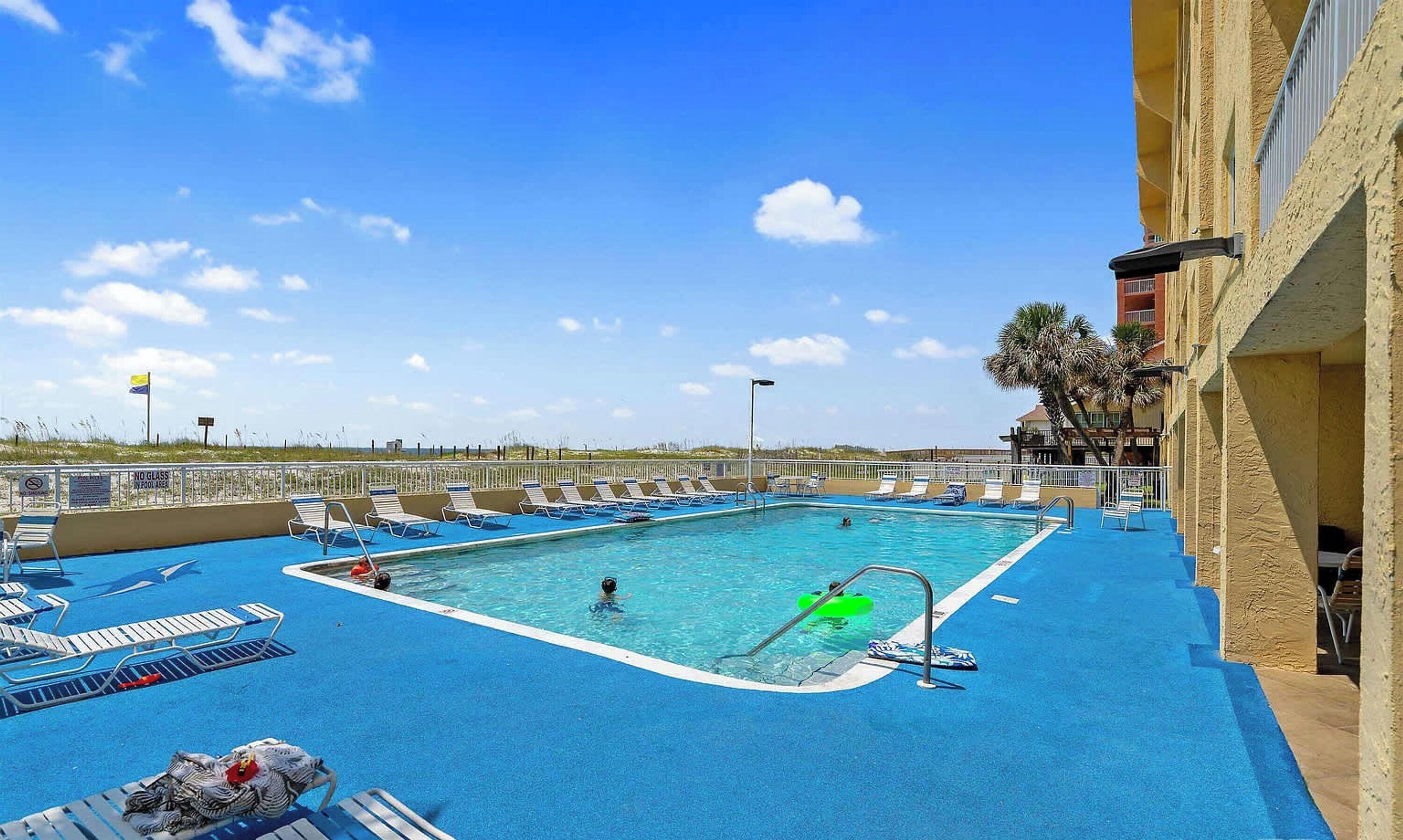 A pool area with lounge chairs, a diving board, and a lifeguard stand.