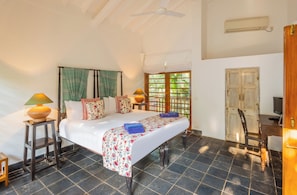 A bedroom with a bed, bedside lamps, a desk, a chair, and a window with a view.