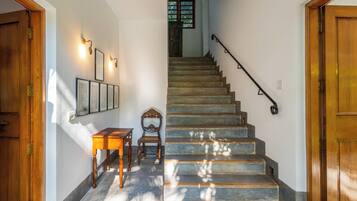 Una escalera con barandilla, una mesa de madera y luces fijadas a la pared.