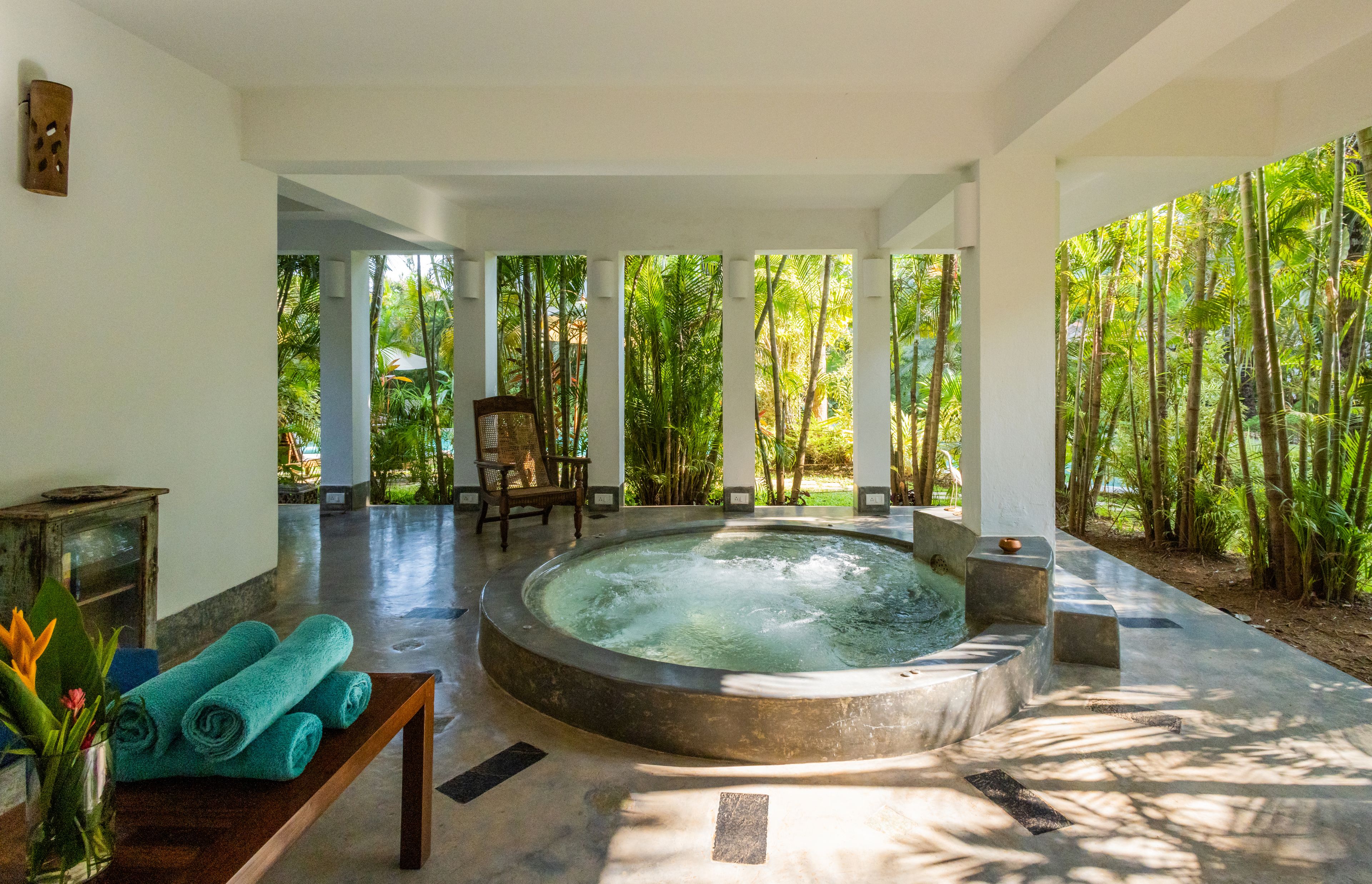 A spa area with a hot tub, a wooden bench, and a table with towels.