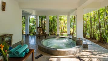 A spa area with a hot tub, a wooden bench, and a table with towels.