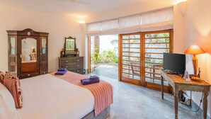 Une chambre à coucher comprenant un lit, une commode, un miroir, une télévision et une vue sur l’extérieur, accessible par une porte coulissante.