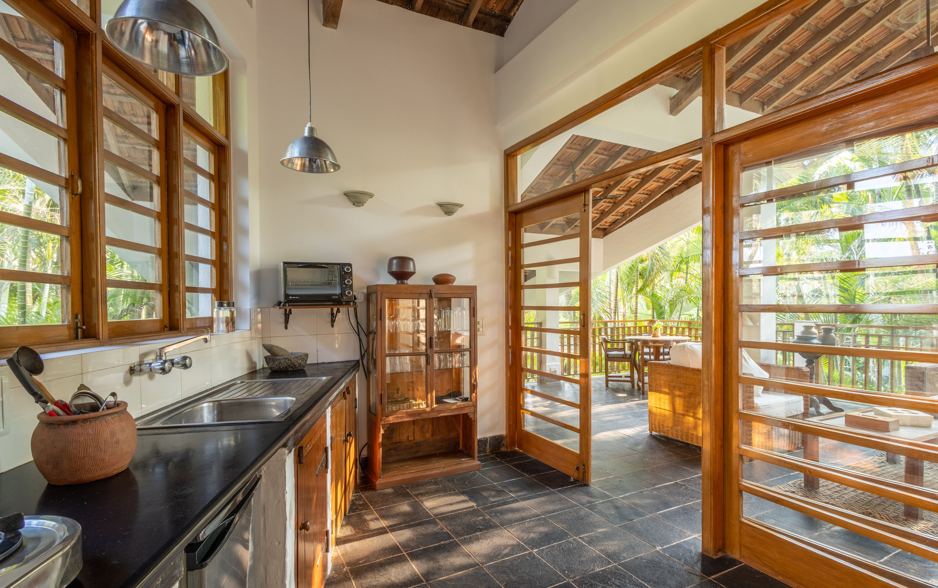 Una cocina con horno empotrado, un lavamanos y una ventana con vistas a un jardín.