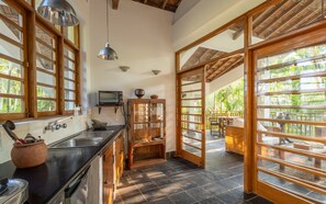 A kitchen with a built-in oven, a sink, and a window overlooking a garden.