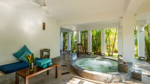 A spa area with a hot tub, a wooden bench, and a view of lush greenery. - Staymaster Bharini 2BR Villa Jet Pool (Nerul)