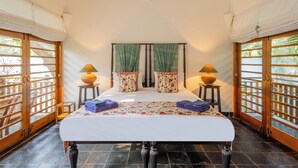 A room with a bed, two side tables, a window with curtains, and a door with a view. - Staymaster Bharini 2BR Villa Jet Pool (Nerul)