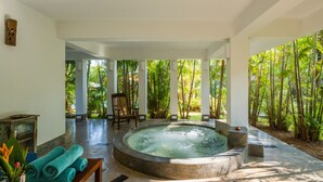 Un espace détente avec un jacuzzi, un banc en bois et une table avec des serviettes.