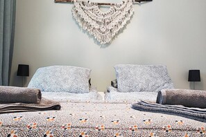 A bed with patterned bedding, two pillows, a macrame wall hanging, and two bedside lamps. - Cozy two bedroom apartment, near Särkänniemi/city (Tampere)