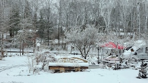 Un espace extérieur enneigé avec une structure en bois, peut-être une cabane, entourée d’arbres.