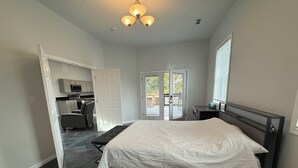A bedroom with a bed, a desk, a chair, and a view of the outside. - 3BR Retreat • Private Patio • Near DC & Pentagon (Springfield)