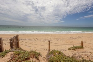 A beach with a wooden fence and sparse vegetation in the foreground. - Casa Evita – Beachfront, Casita, Rocky Point (Puerto Penasco)
