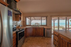 Une cuisine avec vue sur la mer, équipée d’un réfrigérateur, d’une cuisinière et d’un lave-vaisselle.