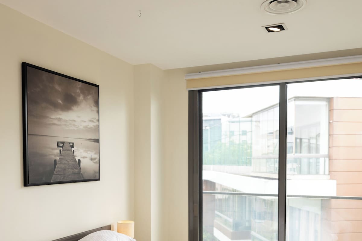 Ein Schlafzimmer mit einem Bett, einem Fenster und einem Bild an der Wand.