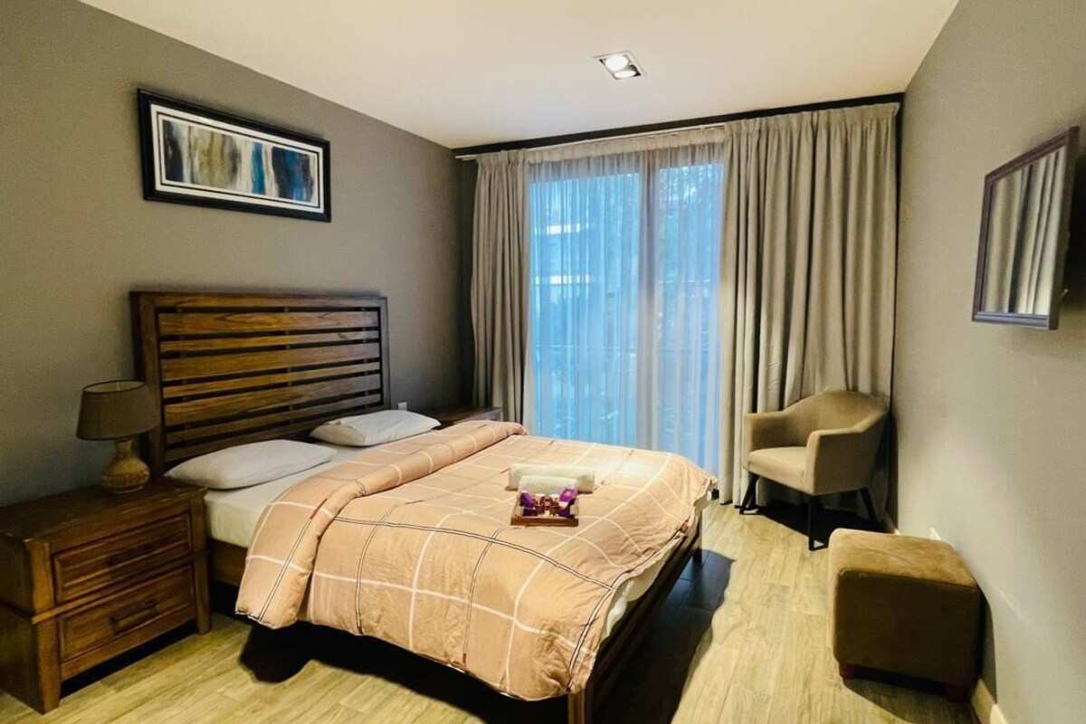 Ein Schlafzimmer mit einem Bett, einem Nachttisch, einem Sessel und einem kleinen Tisch.