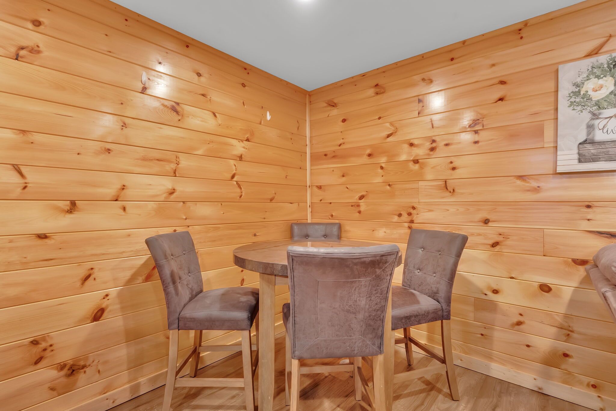Ein Zimmer mit Holzwänden, einem runden Tisch und vier Stühlen.