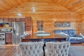 A log cabin interior with a dining table, chairs, a refrigerator, a microwave, and a sofa. - 4BR Bluff Mountain Escape・Near Smokies・Games・Views (Sevierville)