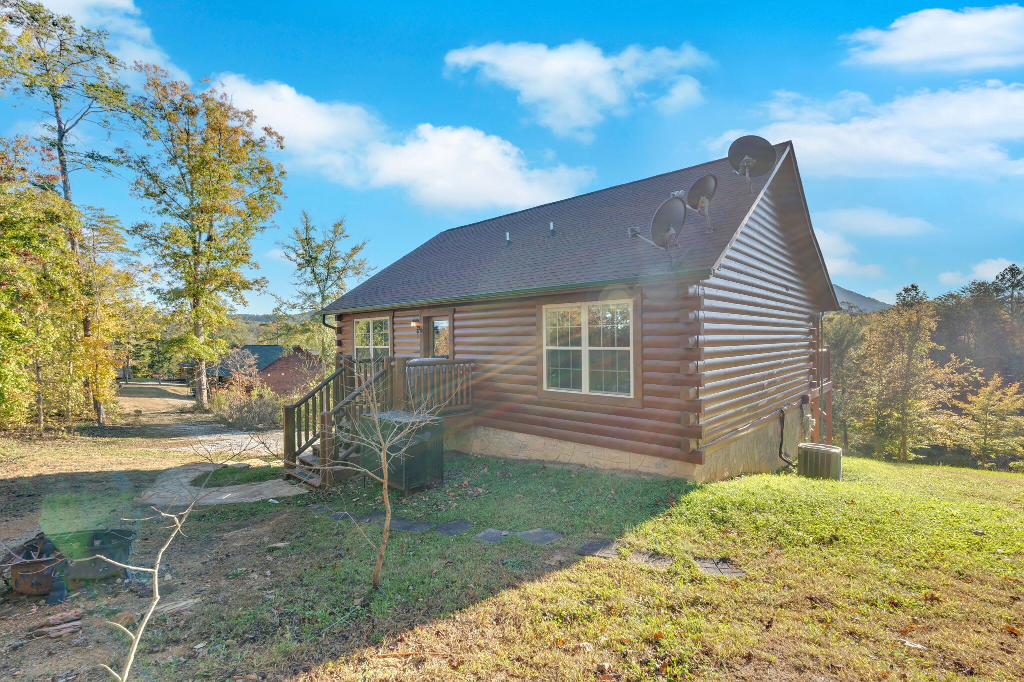 A log cabin with a sloped roof, a front porch, and satellite dishes.