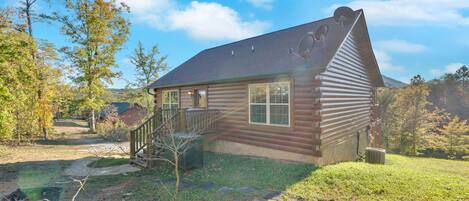 A log cabin with a sloped roof, a front porch, and satellite dishes.
