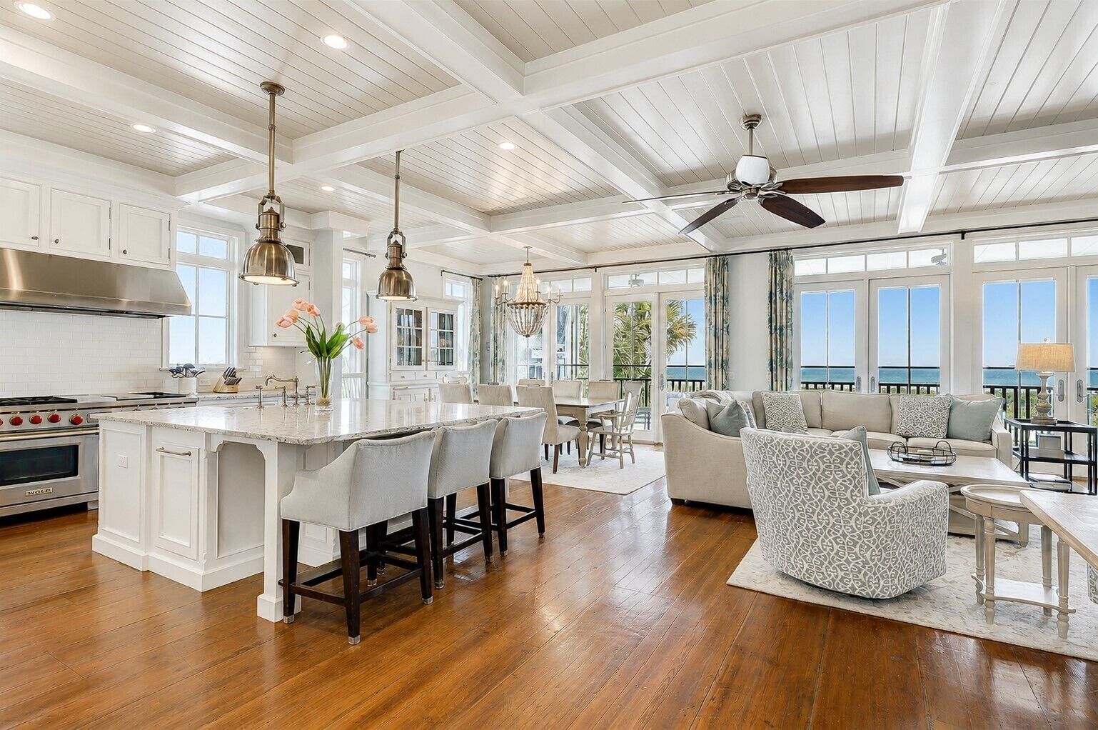 A spacious kitchen with a large island, wooden flooring, and a ceiling fan.